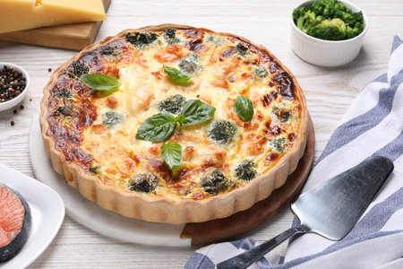 Delicious homemade quiche, ingredients and spatula on tableの写真素材