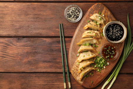Delicious gyoza (asian dumplings) served on wooden table, flat lay. Space for textの写真素材