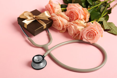 Stethoscope, gift box and flowers on pink background. Happy Doctor's Dayの写真素材