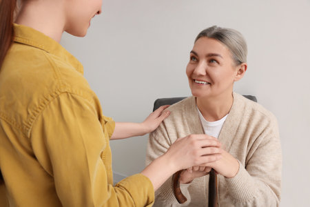 Caregiver and senior woman with walking cane sitting at homeの写真素材