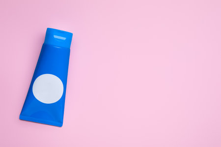 Tube of face cleansing product on pink background, top view. Space for textの写真素材