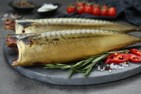 Delicious smoked mackerels and spices on dark gray table, closeup