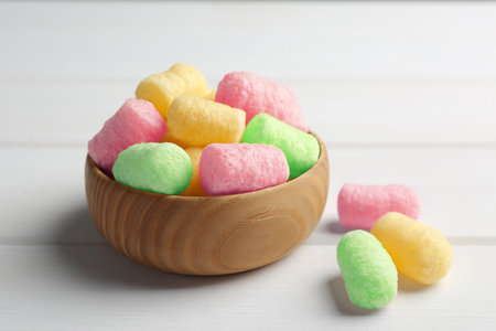 Bowl with colorful corn puffs on white wooden table, closeupの写真素材