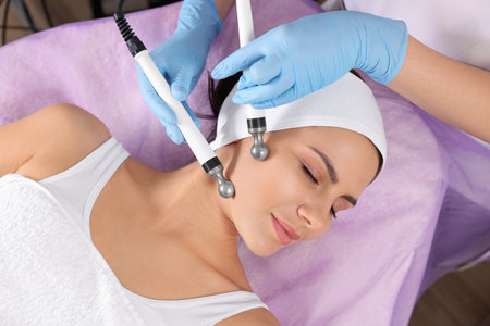 Young woman undergoing cosmetic procedure in beauty salon. Microcurrent therapy