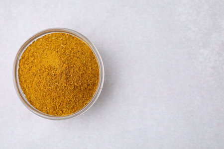 Glass bowl with curry powder on white table, top view. Space for textの写真素材