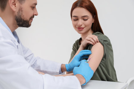 Doctor giving hepatitis vaccine to patient in clinicの写真素材