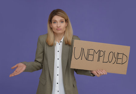 Confused woman holding sign with word Unemployed on violet backgroundの写真素材