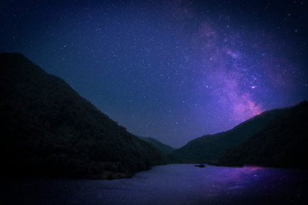 Lake with reflection of starry sky near mountains. Amazing night landscapeの写真素材