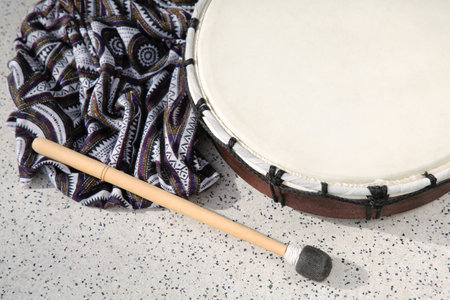 Drum and drumstick on gray table, above view. Percussion musical instrument