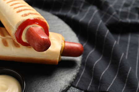 Tasty French hot dogs with different sauces on slate plate, closeup. Space for textの写真素材