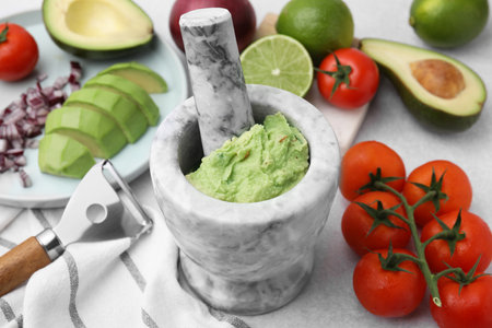 Mortar with delicious guacamole and ingredients on white table, closeupの写真素材