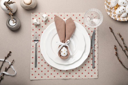 Festive table setting with painted egg, plates and willow twigs, flat lay. Easter celebration
