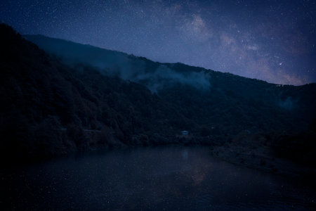 Lake with reflection of starry sky near mountains. Amazing night landscapeの写真素材