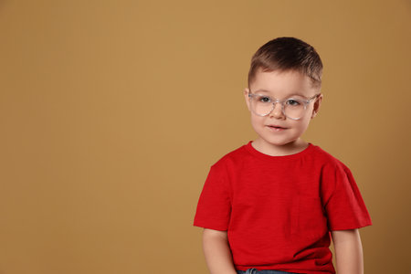 Cute little boy in glasses on pale brown background. Space for textの写真素材
