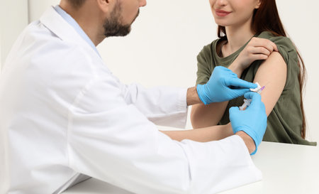 Doctor giving hepatitis vaccine to patient in clinic