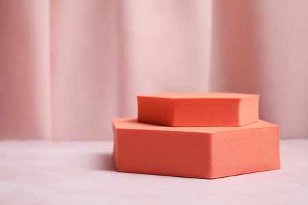 Orange geometric figures on pink marble table, space for text. Stylish presentation for productの写真素材