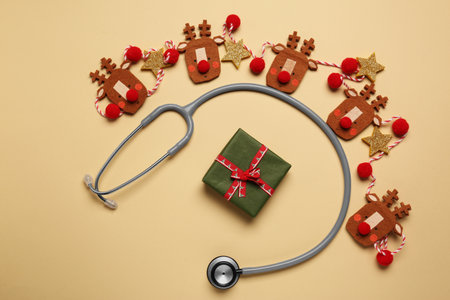 Greeting card for doctor with stethoscope, gift box and Christmas decor on beige background, flat layの写真素材