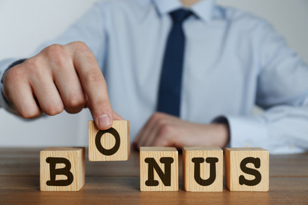 Man making word Bonus of cubes with letters on wooden table, closeupの写真素材