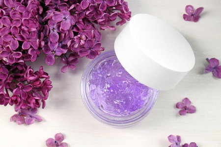 Jar of cosmetic product and lilac flowers on white wooden table, flat layの写真素材