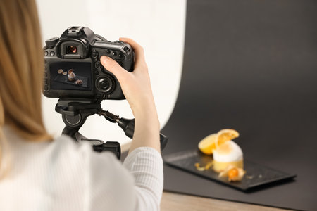 Food stylist taking photo of delicious dessert in studio, closeup. Space for text