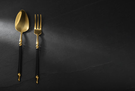 Shiny fork and spoon on black table, flat lay. Space for textの写真素材