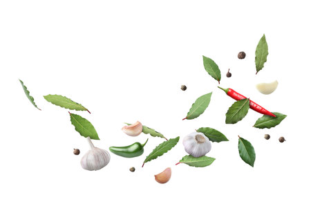 Bay leaves, garlic, black and fresh hot peppers flying on white backgroundの写真素材
