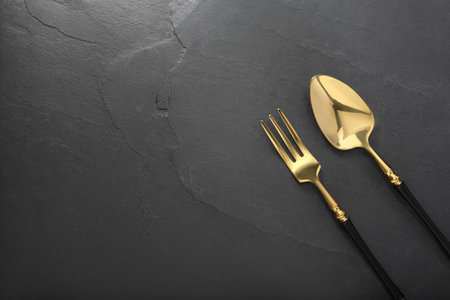 Shiny fork and spoon on black table, flat lay. Space for textの写真素材