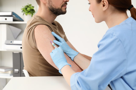 Doctor giving hepatitis vaccine to patient in clinic, closeupの写真素材