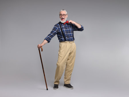 Cheerful senior man with walking cane on gray backgroundの写真素材