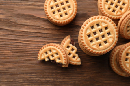 Tasty sandwich cookies with cream on wooden table, flat lay. Space for textの写真素材