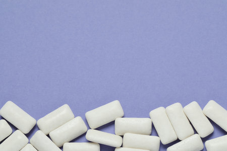 Tasty white chewing gums on light blue background, top view. Space for text