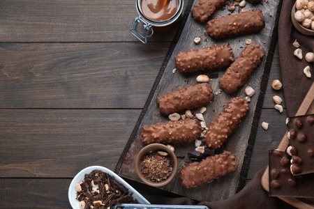 Tasty chocolate bars with caramel and nuts on wooden table, flat lay. Space for text