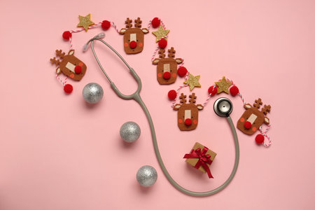 Greeting card for doctor with stethoscope, gift box and Christmas decor on pink background, flat layの写真素材