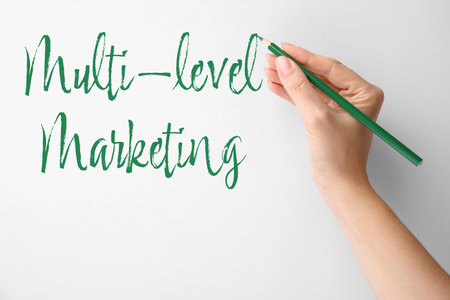 Woman writing text Multi Level Marketing on white background, closeupの写真素材