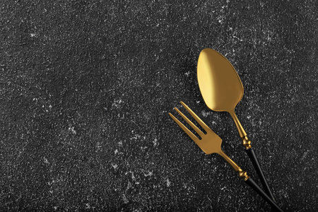 Shiny fork and spoon on black table, flat lay. Space for textの写真素材