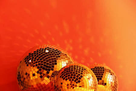 Many shiny disco balls near color wall, toned in orange. Space for textの写真素材