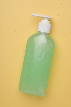 Wet bottle of face cleansing product on pale orange background, top viewの写真素材