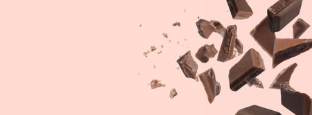 Pieces of chocolate bar falling on beige background, space for text. Banner designの写真素材