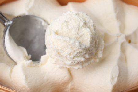 Scoop of delicious vanilla ice cream in container, closeupの写真素材
