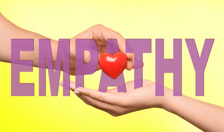Empathy. Man giving heart to woman as symbol of emotional support on yellow background, closeupの写真素材