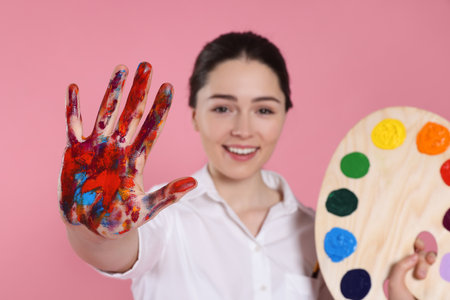Woman with painted palm and palette on pink background, selective focus. Young artistの写真素材