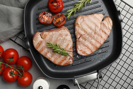 Delicious tuna steaks with rosemary and tomatoes on gray table, flat layの写真素材