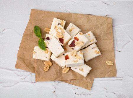 Pieces of delicious nutty nougat on white textured table, top viewの写真素材