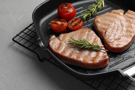 Delicious tuna steaks with rosemary and tomatoes on gray table, closeupの写真素材