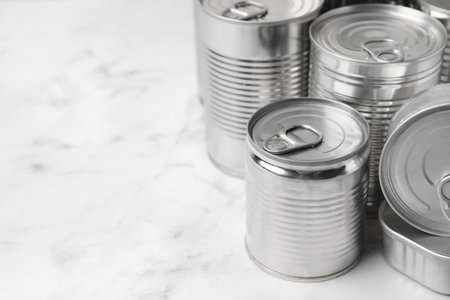 Many closed tin cans on white marble table, closeup. Space for textの写真素材