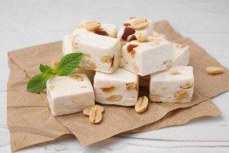 Pieces of delicious nutty nougat on parchment paper, closeupの写真素材
