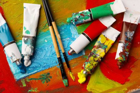 Tubes of colorful oil paints and brushes on canvas with abstract painting, flat layの写真素材
