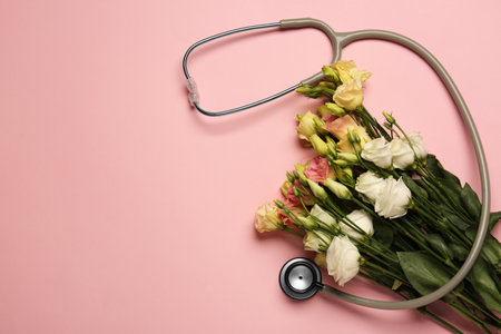Stethoscope and flowers on pink background, flat lay with space for text. Happy Doctor's Dayの写真素材