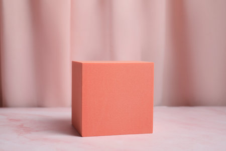 Orange geometric figure on pink marble table. Stylish presentation for productの写真素材