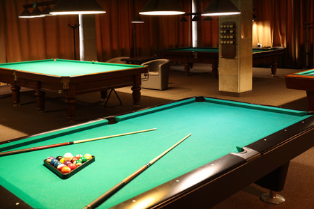 Billiard tables with balls and cues in club